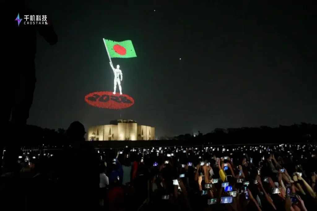 Crostars drone light show above Dhaka Bangladesh parliament building — drones forming a figure holding the Bangladesh national flag before a large crowd, Pohela Boishakh celebration 2025