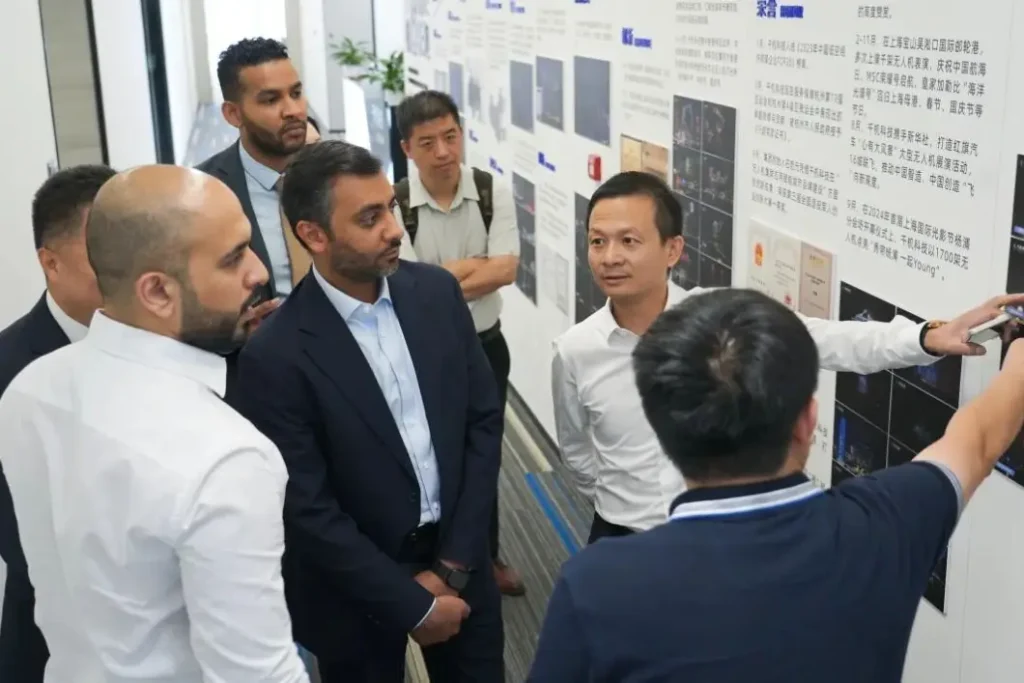 UAE delegation viewing Crostars global drone show portfolio during showroom tour at Shanghai headquarters, July 2025 — Dubai performance photos visible on wall