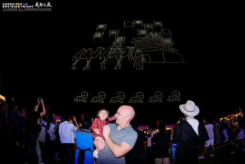 Crostars drone light show night performance, Trip.com Group Global Partner Gala, Chengdu May 2025 — international visitor holding a child in the foreground watching the drone performance