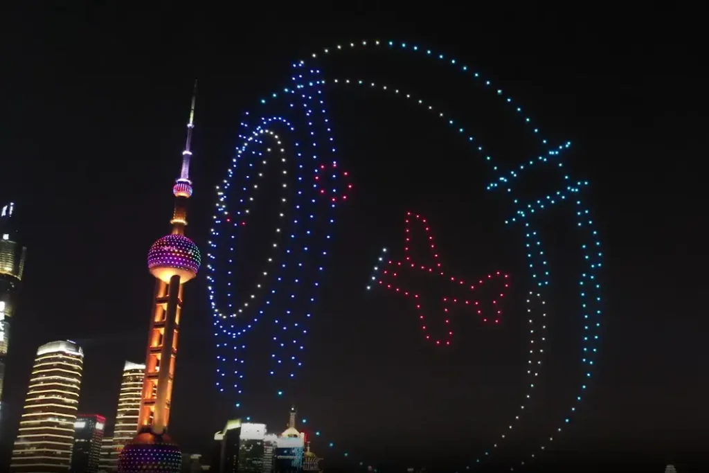 Crostars drones forming Longines winged hourglass logo in blue and red above Shanghai Bund with Oriental Pearl Tower, 2020