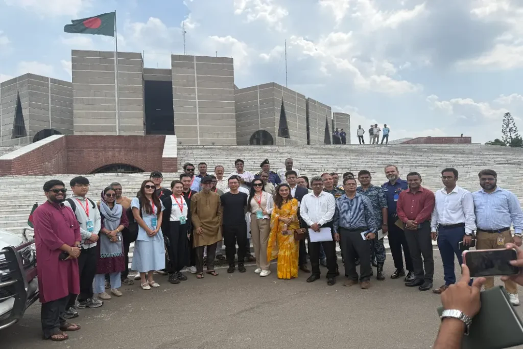 Crostars Chinese team and Bangladeshi officials on steps of Bangladesh National Parliament, Dhaka, Bangladesh national flag flying above, April 2025
