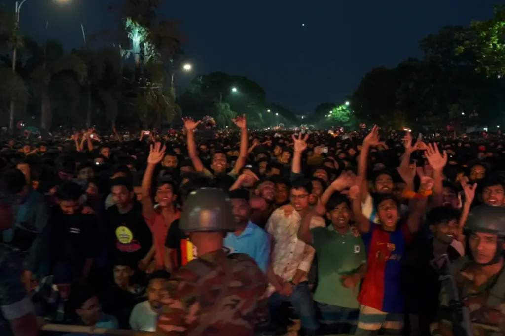 Crowd of over one million at Pohela Boishakh drone show in front of Bangladesh National Parliament, Dhaka, April 14 2025 — security personnel in helmets in foreground, crowd cheering with raised arms